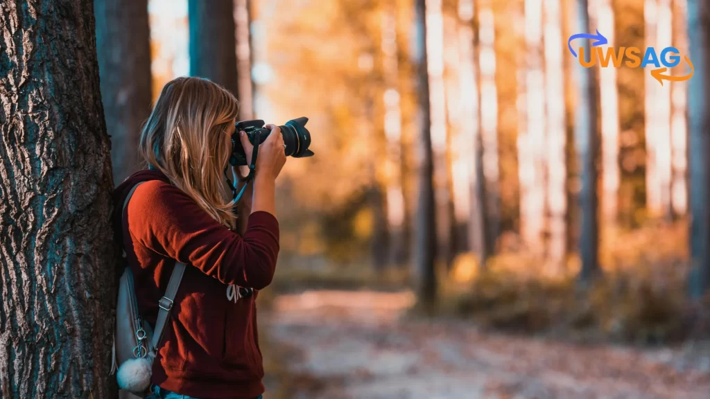 "ILikeComox: Woman taking a photograph in a serene autumn forest."