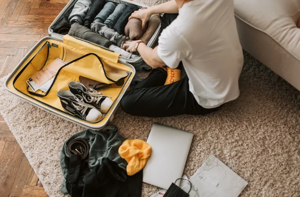 A man neatly rolling clothes in a suitcase for a well-packed trip – what is day packing for a hassle-free journey?